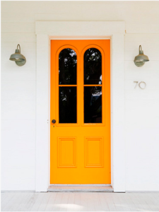 Bright orange door against a white house.