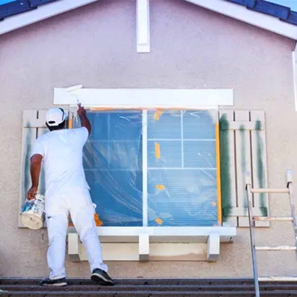 Professional painter painting exterior of outside window trim white