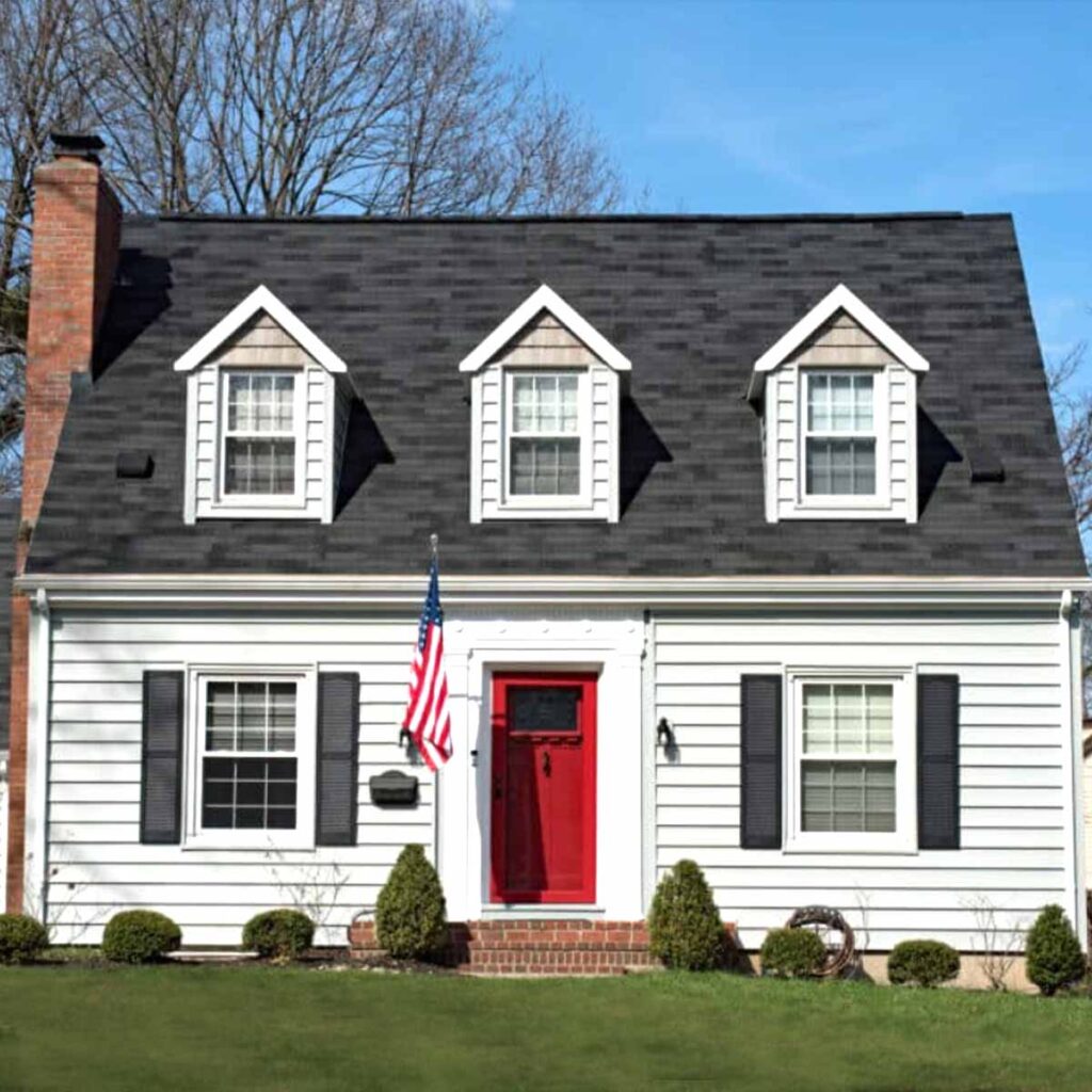 Exterior of home with white paint, bright red door and black trim and black roof