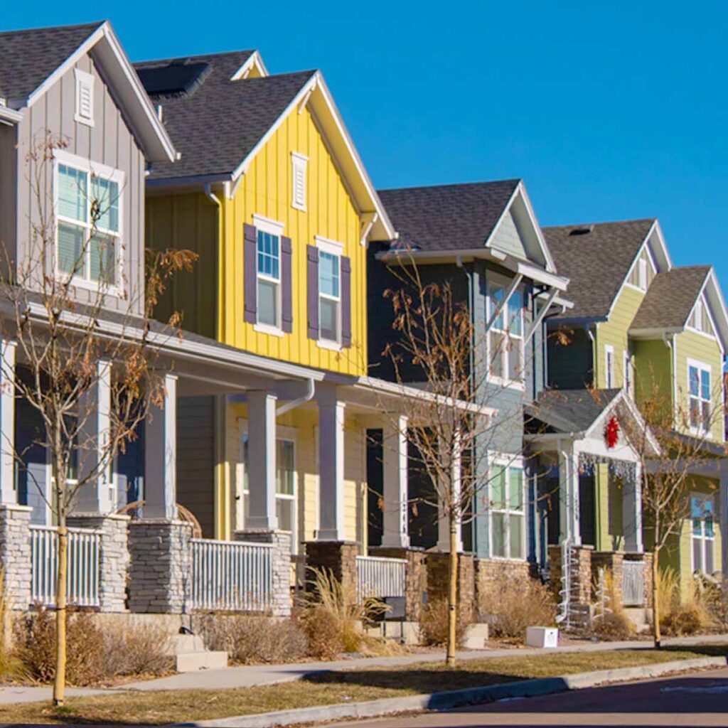 Group of four homes that are bright yellow, green and tan a great example of exterior painting