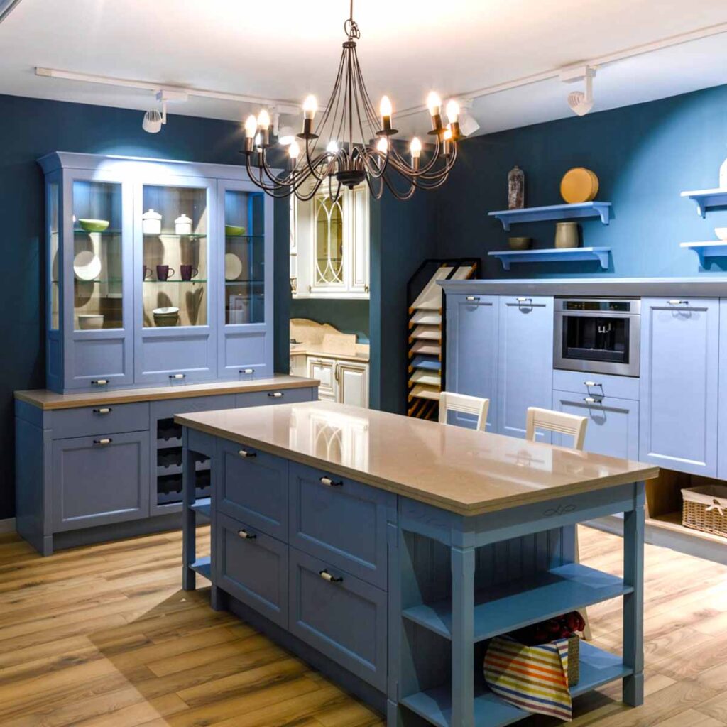 Interior of kitchen with brown marble countertops, blue cabinetry and blue walls